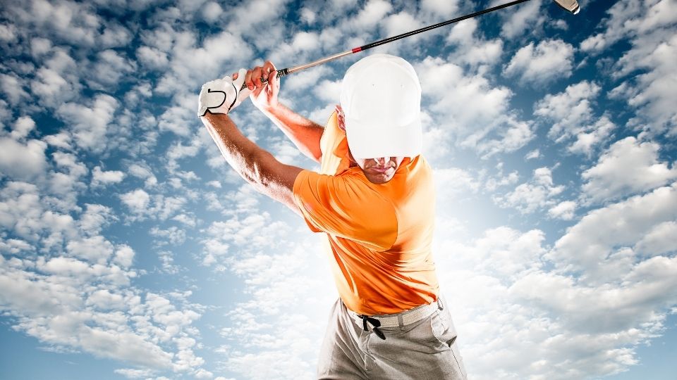 A man swinging at the sky with his golf club.