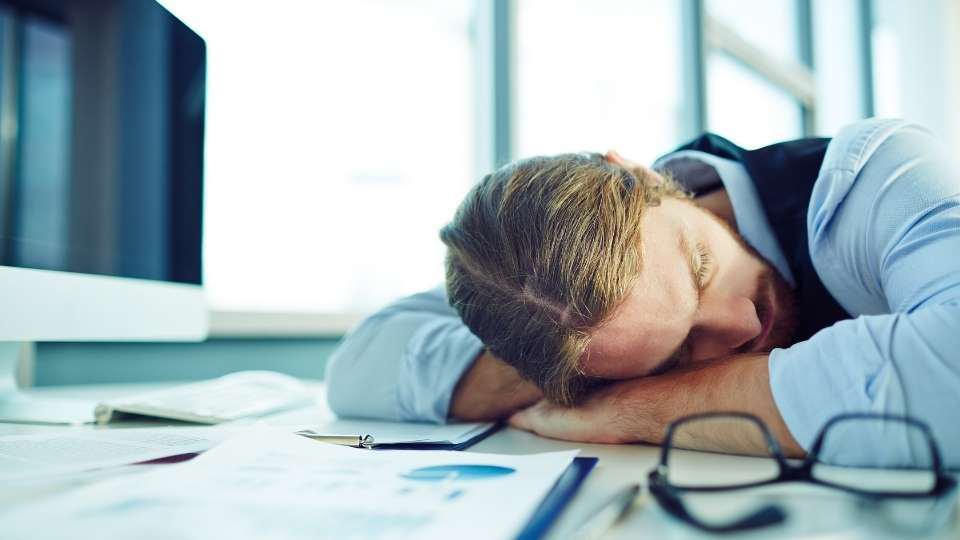 A person is sleeping on the table with their head down.