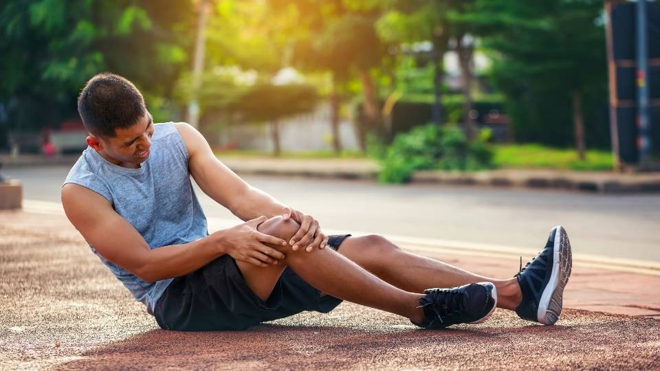 A man sitting on the ground with his hands in his legs.