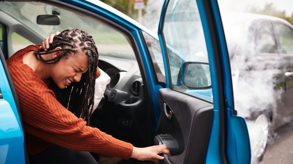 A woman is putting her hands on the door of a car.