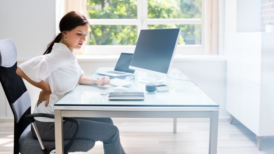 A woman sitting at a desk with two laptops.