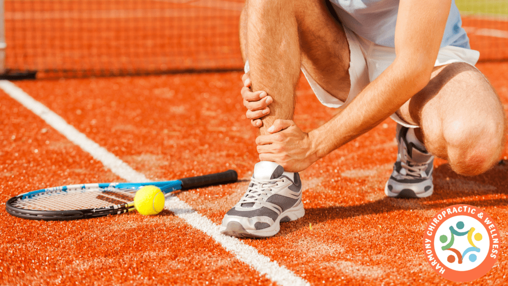 A tennis player is holding his ankle while he has just hit the ball.