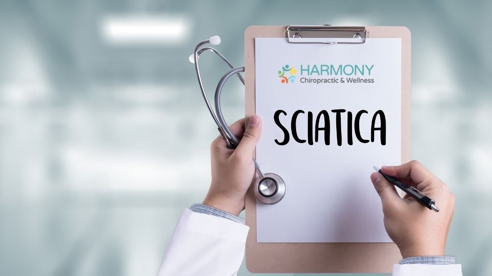 A doctor holding up a clipboard with the word sciatica written on it.