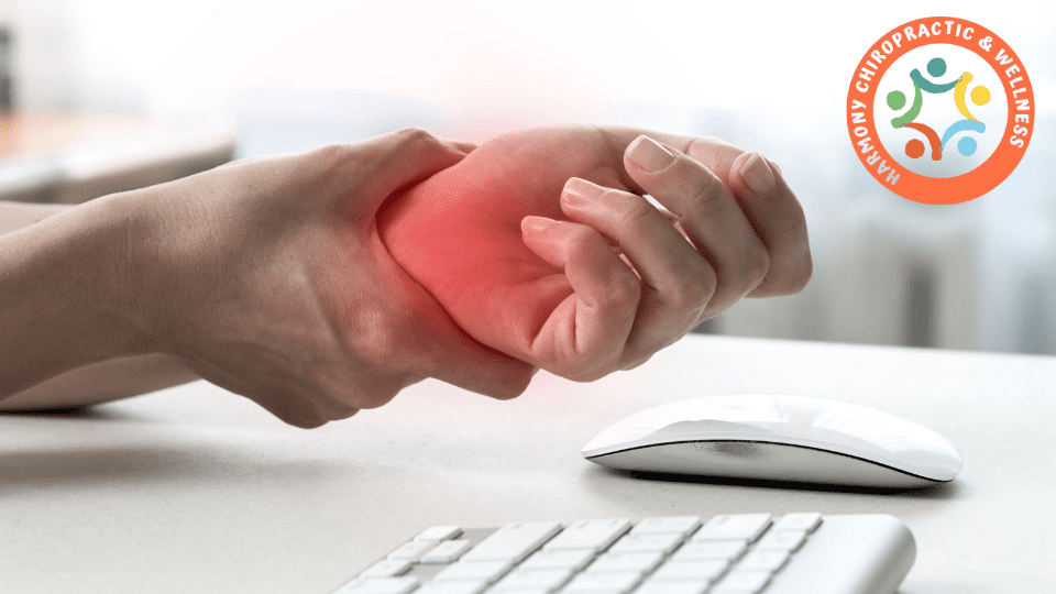 A person holding their hand in pain near a computer keyboard.
