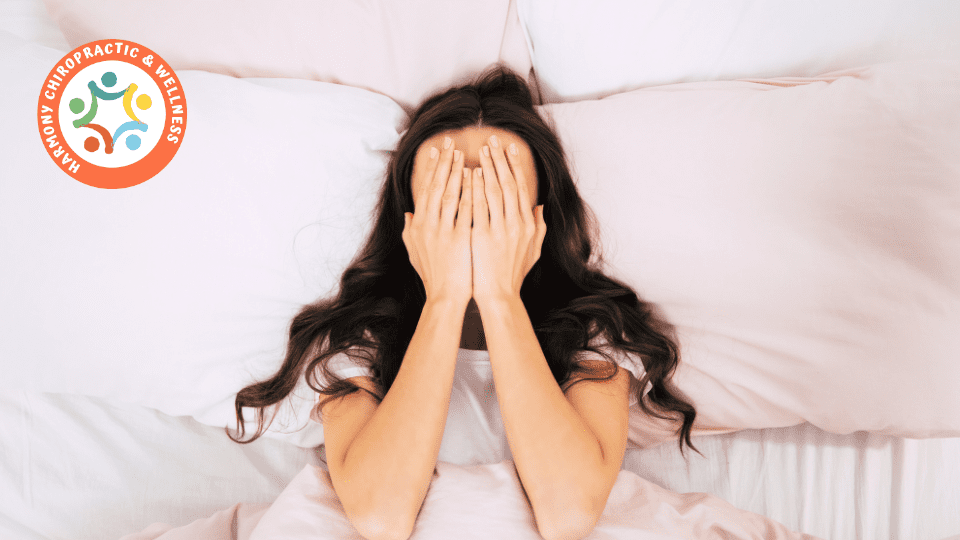 A woman covers her face while lying in bed.