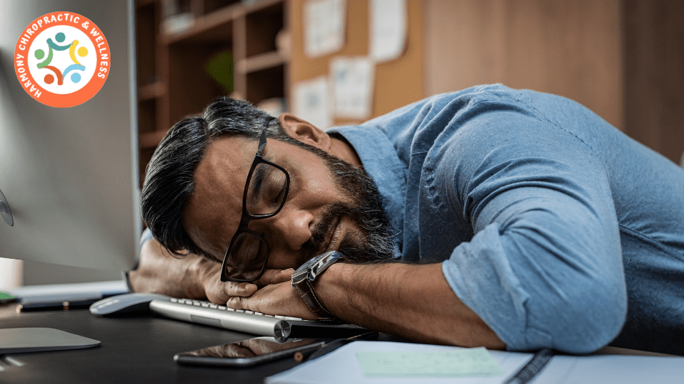 A man with glasses is sleeping on his desk