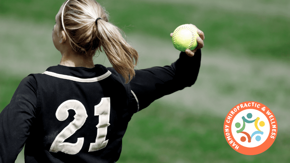 A girl in black and white uniform throwing a ball.