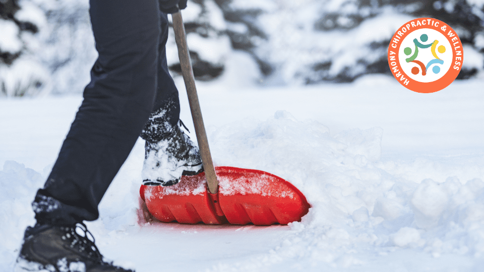 A person shoveling snow with a red shovel.